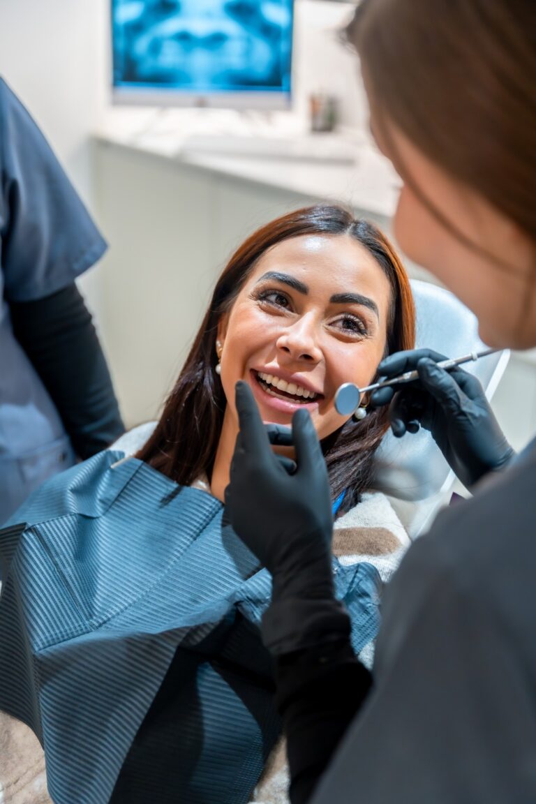 Smiling patient in a dental chair during a consultation or treatment visit with clinician nearby