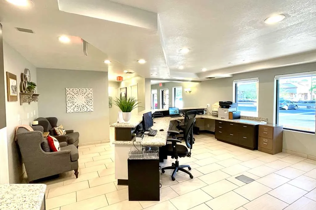 Modern dental office reception area with tiled flooring, workstations, front desk, and bright overhead lighting