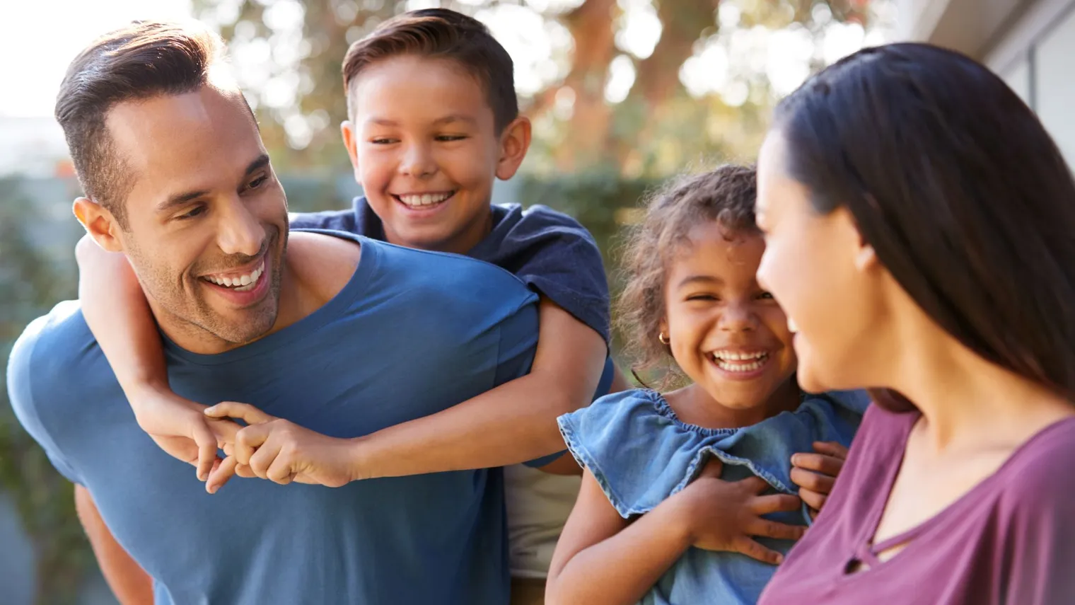 Smiling children and parent together outdoors, used for family-focused dental marketing imagery