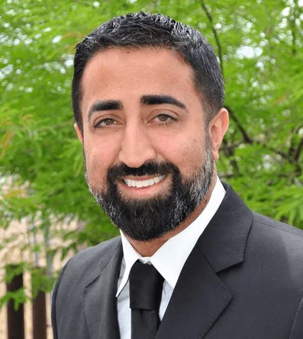Professional headshot of a male dental team member with beard, suit jacket, and tie outdoors