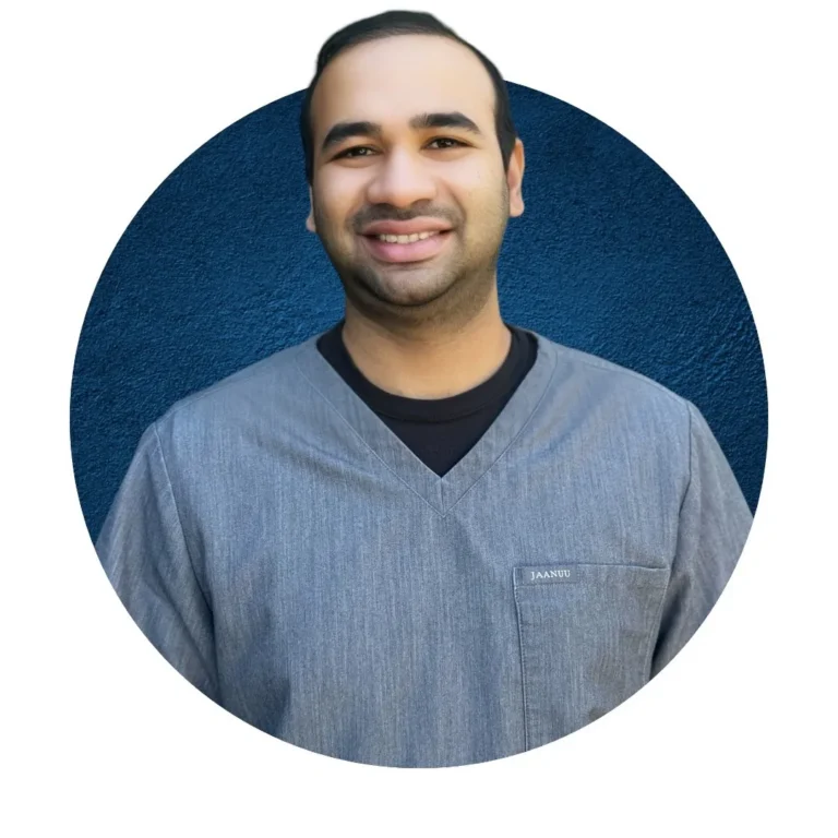 Professional headshot of a smiling dental team member in blue scrubs against a solid blue background