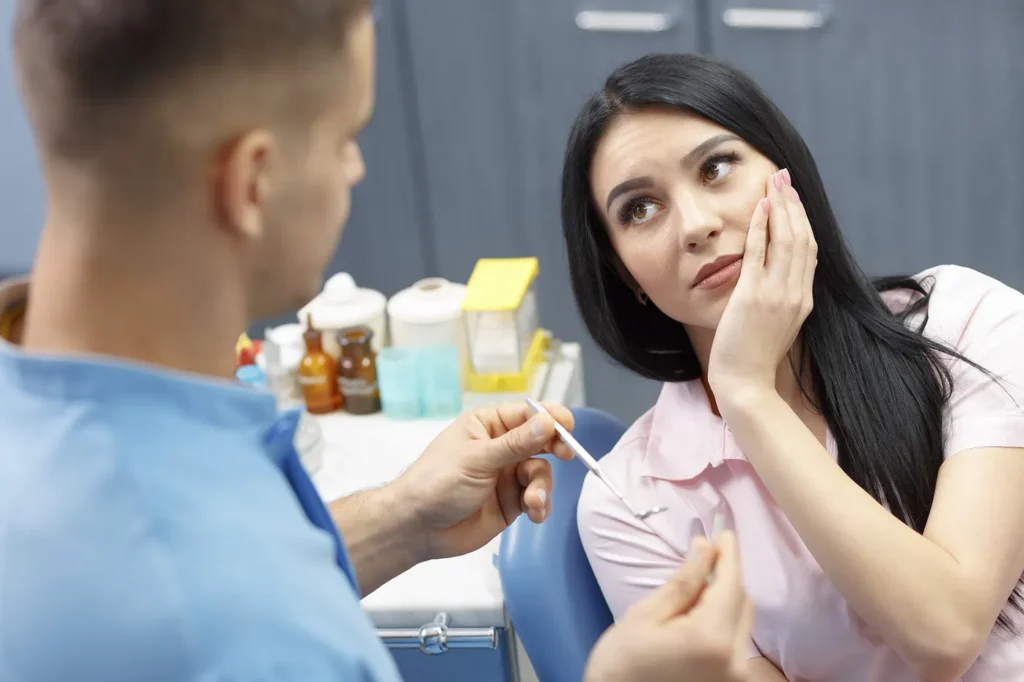 Patient speaking with a clinician during a dental consultation while seated in a treatment room