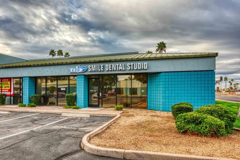 Exterior view of Smile Dental Studio with blue facade panels, glass storefront, and signage above the entrance