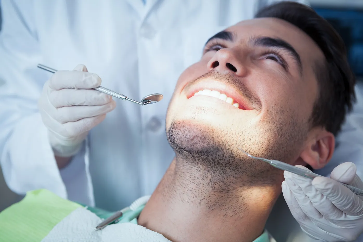 Patient reclining in a dental chair while receiving care under bright clinical lighting
