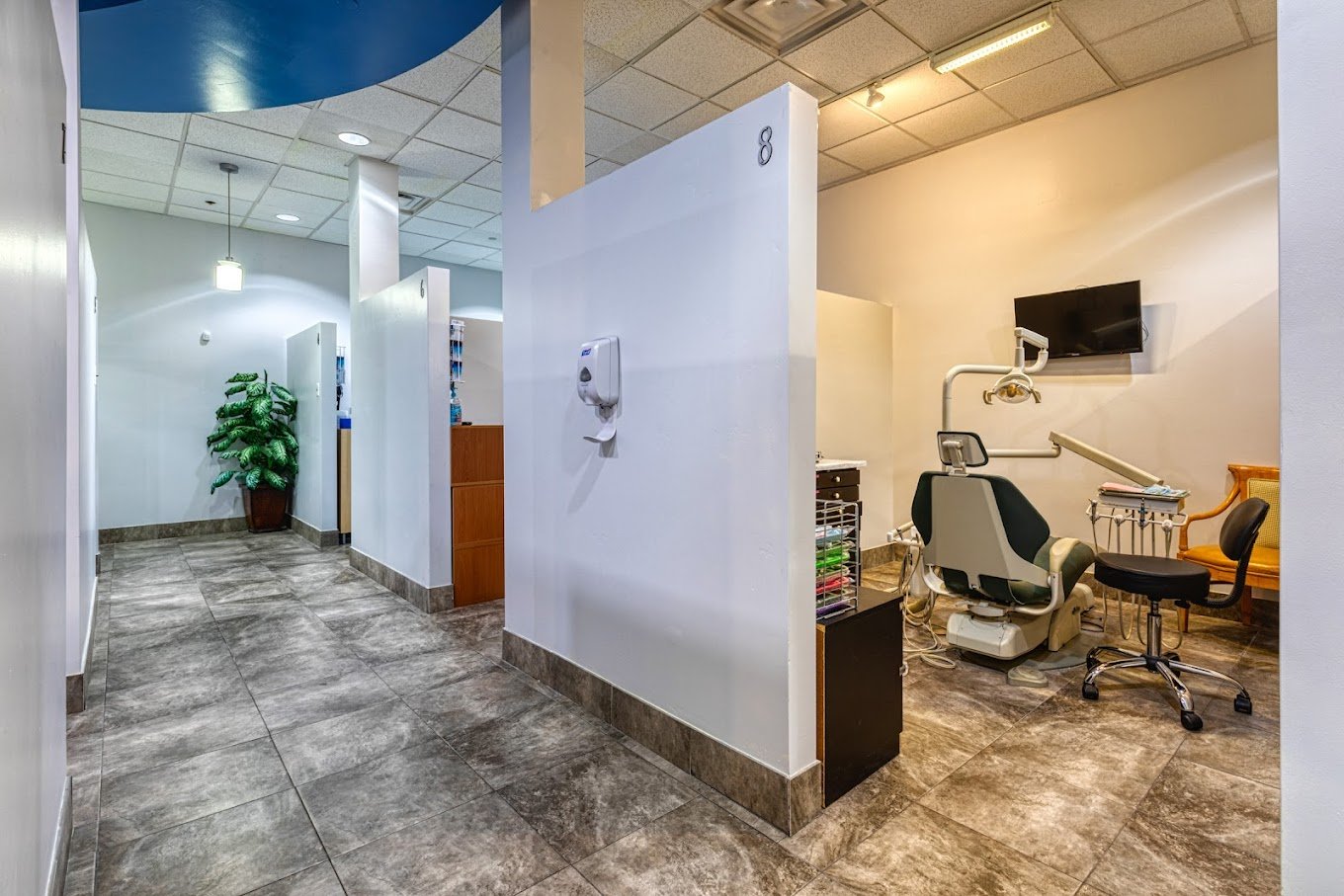 Bright operatory bay with partition walls, tiled flooring, mounted equipment, and open clinical layout