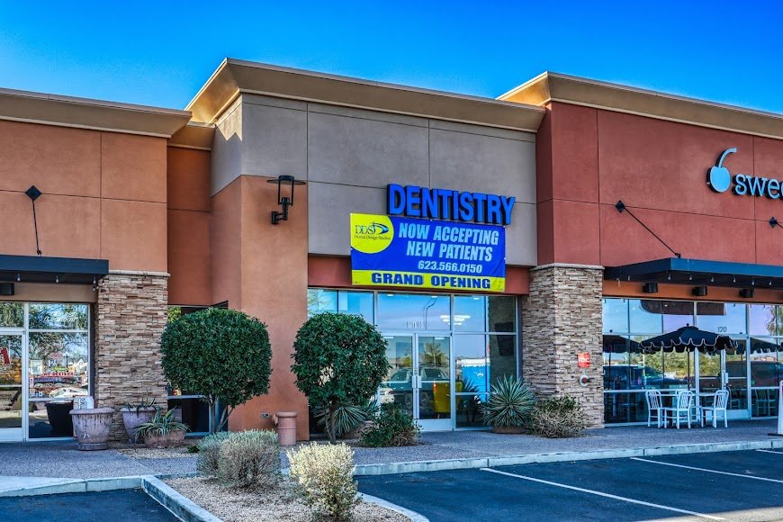 Exterior view of a dental office storefront with Dentist signage, stone accents, and landscaped entryway