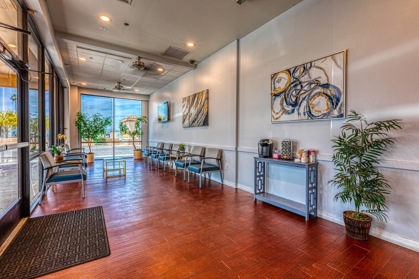 Spacious dental lobby with polished wood floors, seating along the walls, front windows, and decorative console table