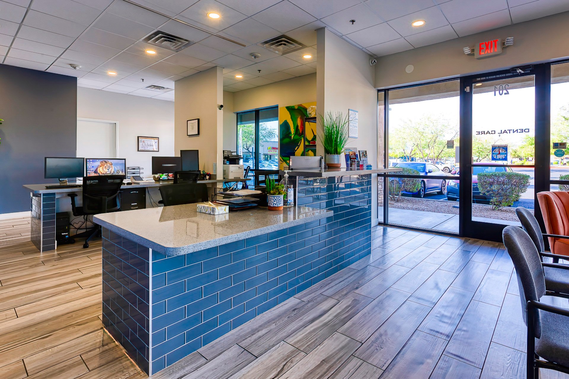 Dental office reception area with blue front desk, open lobby, and large front windows bringing in natural light