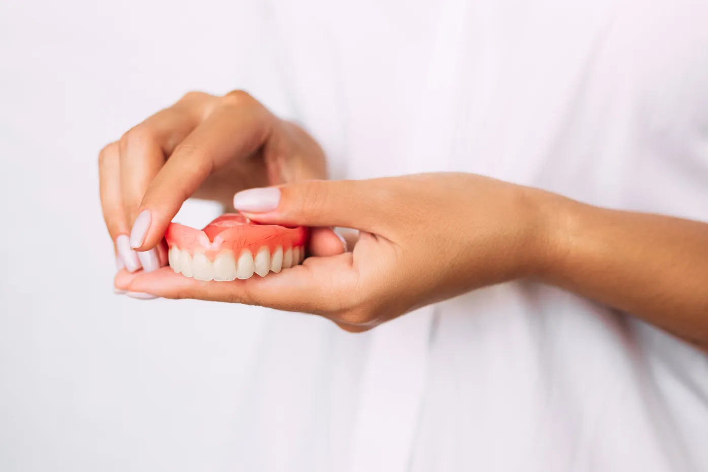 Hands holding a dental model with visible teeth for patient education or treatment demonstration