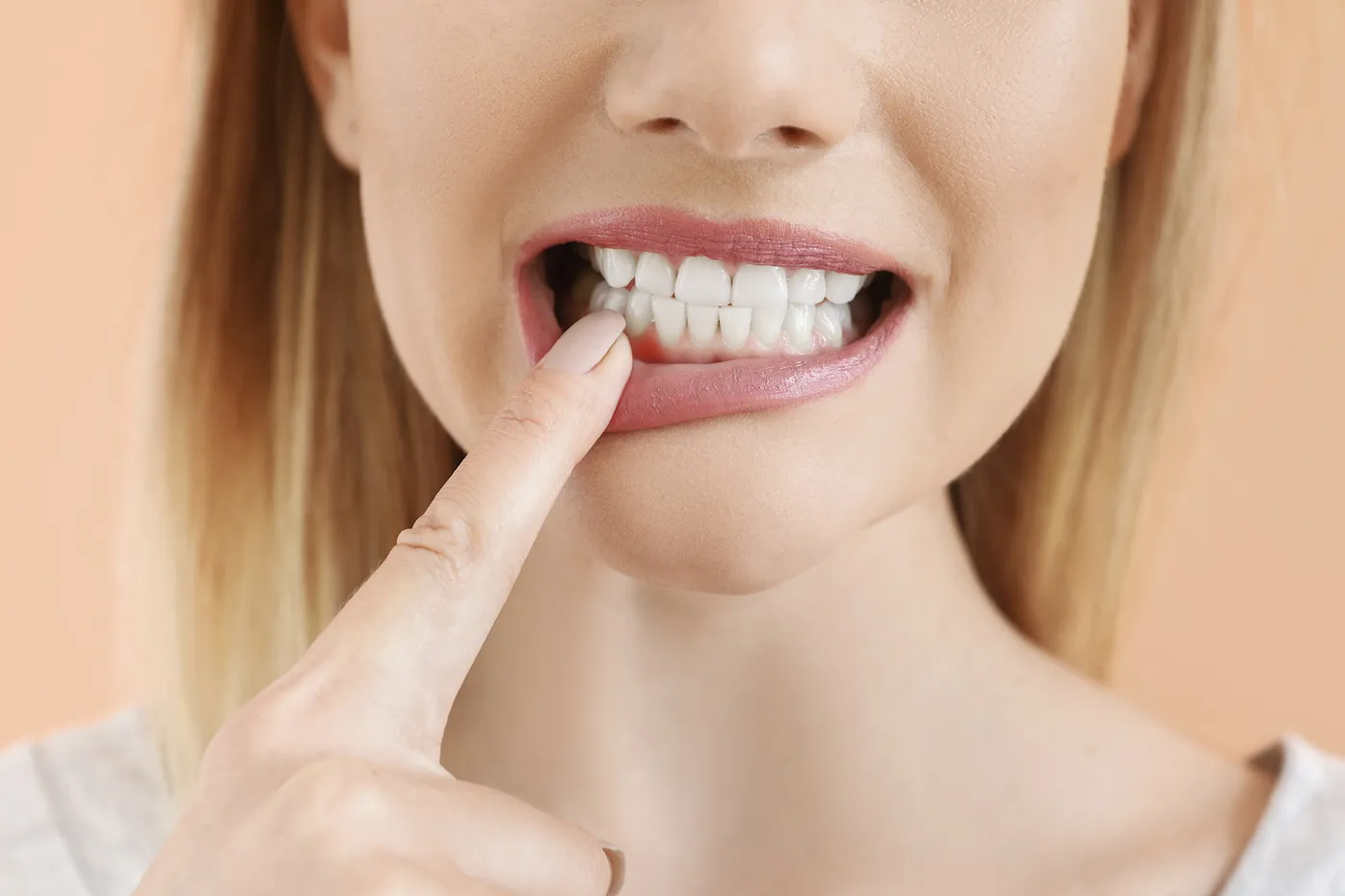 Close-up of teeth and smile with a finger pointing to the front tooth for cosmetic or dental health emphasis
