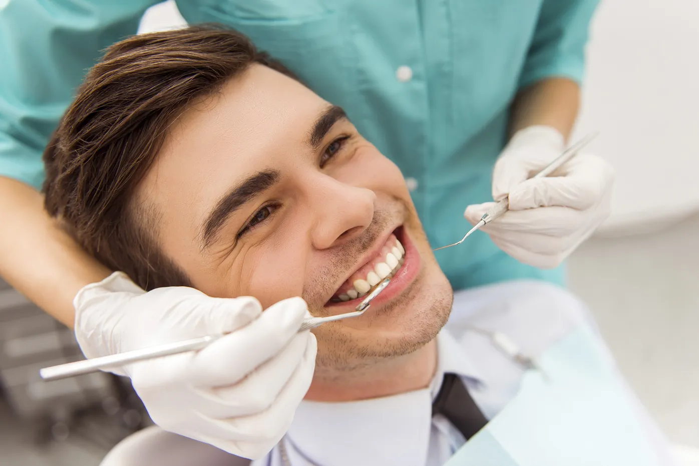 Smiling patient receiving a dental exam while reclining in a treatment chair during a routine visit