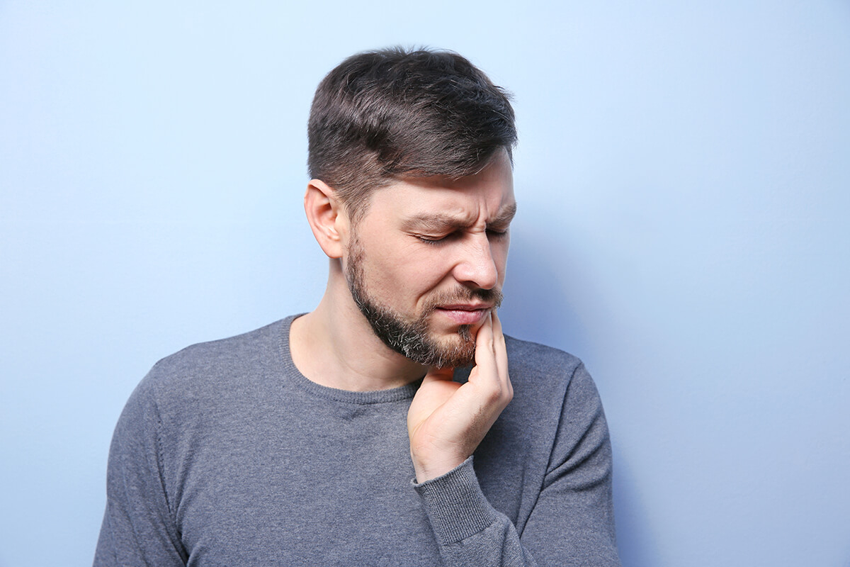 man holding his jaw in pain while experiencing a possible dental emergency in the Greater Phoenix area