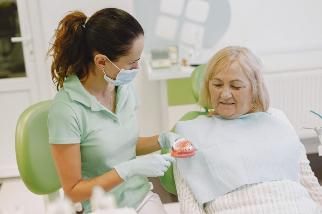 dentist discussing denture fit and care with an older patient during a dental visit