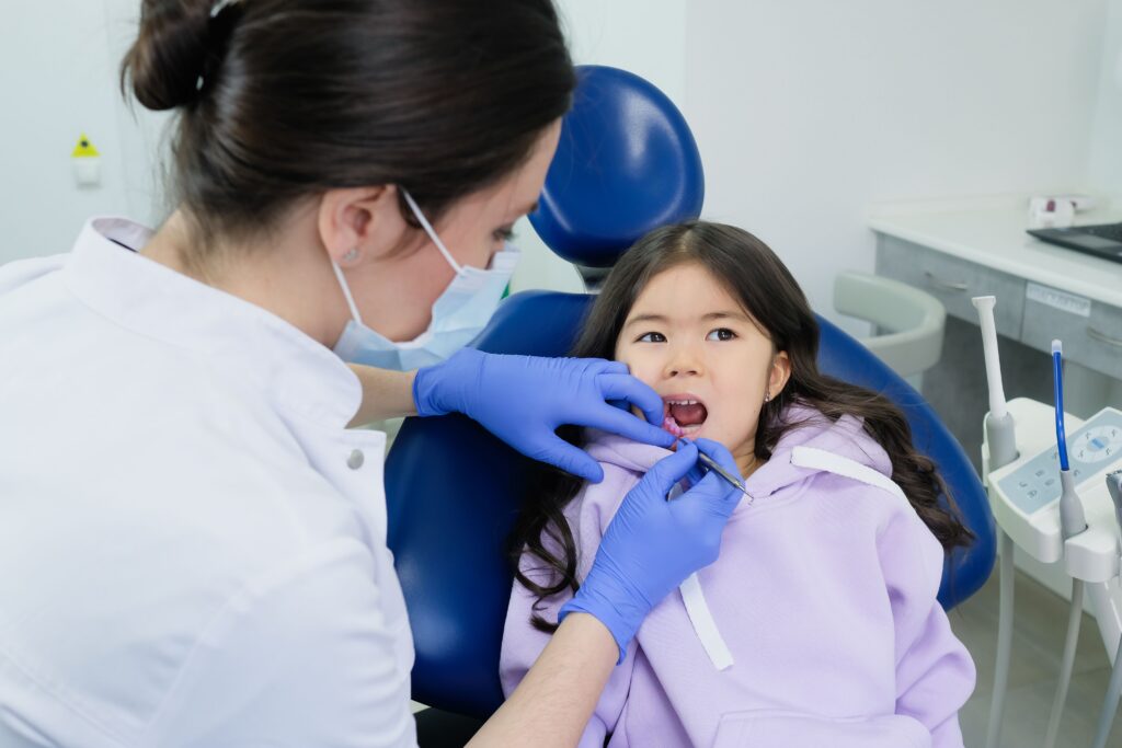 Child receiving a dental examination as part of preventive care to assess teeth for potential dental sealants.