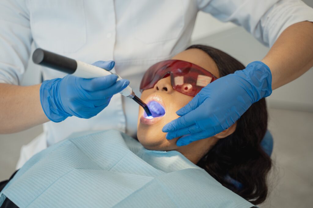 dentist using a curing light during a dental bonding procedure
